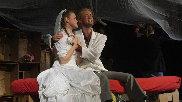 Polly Peachum (Camille Zenses) im Liebeswahn: Sie hat Macheath alias Mackie Messer (Winona Giese) geheiratet und sitzt nun mit ihm auf dem Ehebett.  Foto: Joachim Rübel