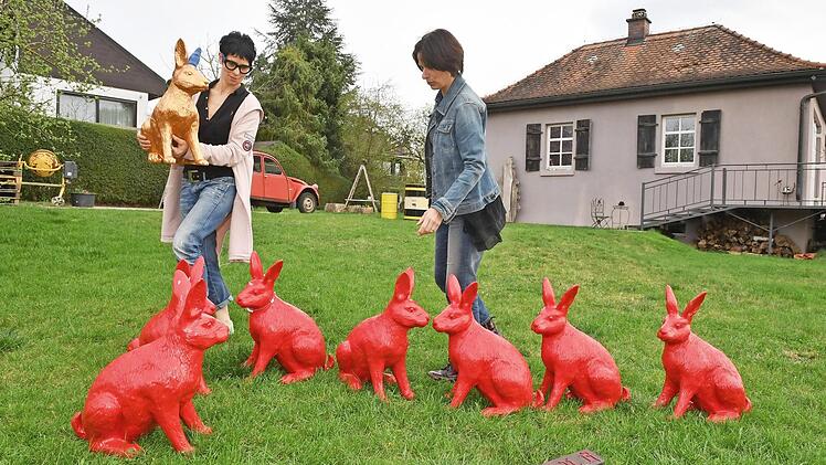 Die Hasenversammlung in Bamberg-Südwest. Zur Komplettierung der um einen Hasen geschrumpften Gruppe bringt Barbara Bollerhoff den goldenen Hasen mit dem blauen Ohr in den Garten. Rechts ihre Freundin und Künstler-Kollegin Petra Ringelmann  Fotos: Ronald Rinklef
