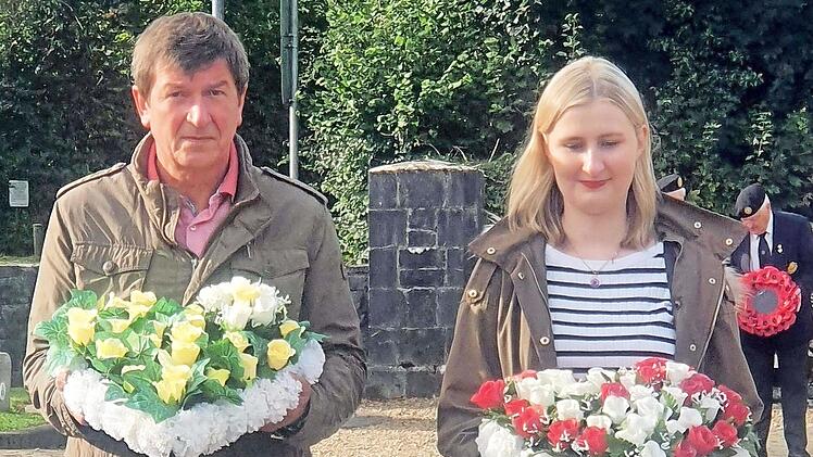 Reiner Schunder und Valerie Schullan bringen Kränze zum Friedensdenkmal.