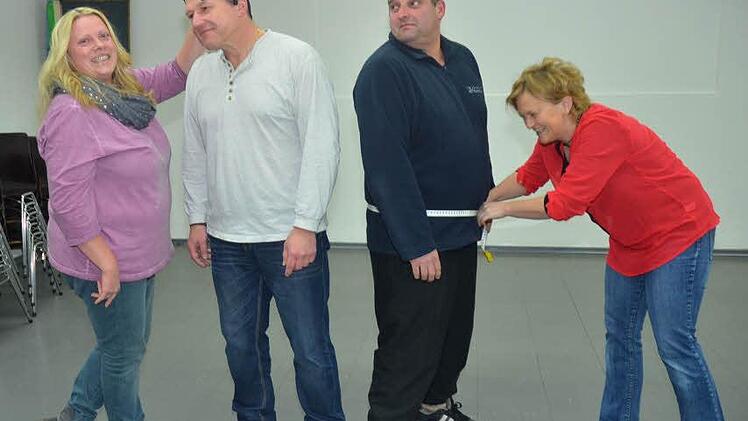 Mehrere Male müssen die Trainerinnen Renate Barnickel und Silke Tannhäuser nach den Proben, zwischen September bis Januar, bei den Herren der Schöpfung Maß nehmen, und so manches Kostüm muss nochmals zugeschnitten und erweitert werden. Von links: Hier müssen still stehen, Michael Leitz für die Perückenanprobe mit Renate Barnickel und Silke Tannhäuser, die Maß bei Michael Dorschner für die Anfertigung des Tanz- Kostüms nimmt. Foto: K.- H. Hofmann