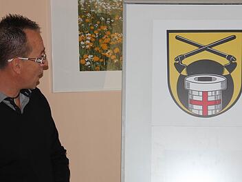 Ortssprecher Andreas Leibold bewundert das neue Dorfwappen von Reutersbrunn. Ein Brunnen, die Waldrodung und Eberns Stadtfarben dominieren. Foto: Ralf Kestel