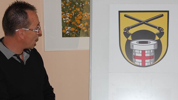 Ortssprecher Andreas Leibold bewundert das neue Dorfwappen von Reutersbrunn. Ein Brunnen, die Waldrodung und Eberns Stadtfarben dominieren. Foto: Ralf Kestel