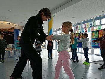 Janine Böhme zeigt den Schülern spielerisch, wie sie sich gegen Schläge oder Tritte wehren. Foto: Franziska Rieger