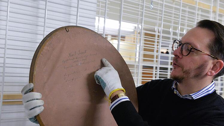 Alexander Süß zeigt auf die alte Schrift auf der Bildrückseite.  Foto: Ronald Rinklef