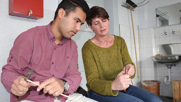 Fachlehrerin Brigitte Klitzner erklärt dem Schüler Zabiullah, wie man Weidenruten spaltet, bevor es an den Hobel geht. Foto: Popp