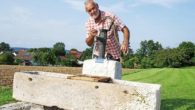 Otto Fischer legt letzte Hand am Wolfsdorfer Brunnen auf dem Sportplatz an, der vor wenigen Tagen aufgestellt wurde. Fotos: Thomas Hümmer