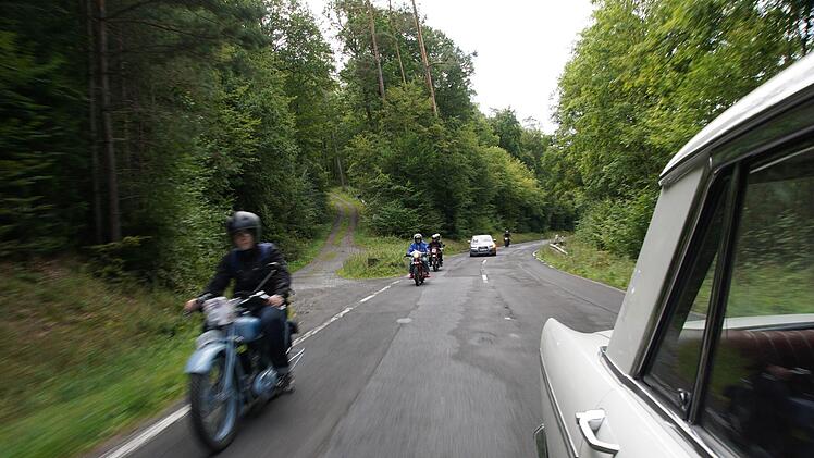Ein Auto überholt auf der Strecke eine Motorrad-Teilnehmergruppe.Foto: Arkadius Guzy