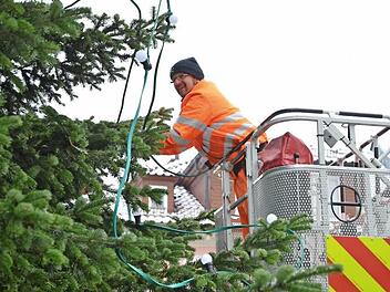 Von der Drehleiter der Feuerwehr aus bestückt Günther Franke den großen Weihnachtsbaum auf dem Marktplatz mit 200 Lämpchen für die Festbeleuchtung. Fotos: Rainer Lutz