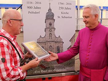 Berthold Moser (links) überreichte an den Würzburger Domdekan Prälat Günter Putz das neue Ortsbuch von Prölsdorf.  Foto: Klaus Schmitt