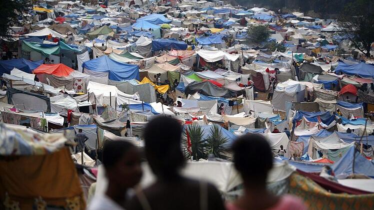 Frauen schauen in Port-au-Prince auf ein Lager, in dem 2010 &Uuml;berlebende des Bebens versorgt wurden. Oxfam-Mitarbeiter sollen sich w&auml;hrend ihres Hilfseinsatzes Prostituierte haben bezahlen lassen.  David Fernandez, dpa