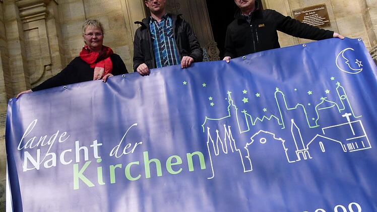 Andrea Hofmann, Jochen Högendörfer und Ulrich Ortner (v.l.) präsentieren vor der St. Jakobskirche das Banner zur "Langen Nacht der Kirchen".   Fotos: Marion Krüger-Hundrup