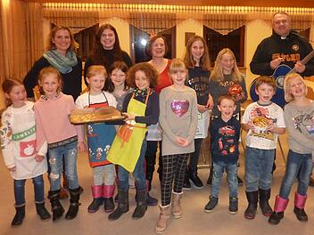 Die vergn&uuml;gte Aschacher Backtruppe freut sich mit dem B&uuml;chereiteam &uuml;ber die leckeren Pl&auml;tzchen: (hinten, von links) Verena Schwerteck, Melina H&ouml;chemer, Barbara Seufert  und (ganz rechts) Pfarrer Michael Kubatko mit seiner Gitarre. Foto: Claudia Horn