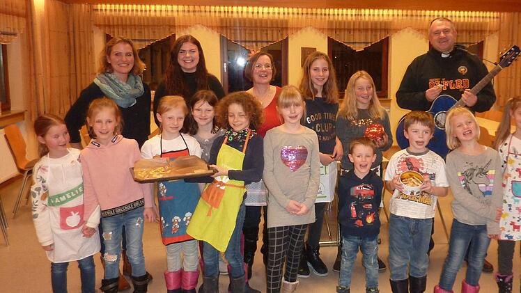 Die vergn&uuml;gte Aschacher Backtruppe freut sich mit dem B&uuml;chereiteam &uuml;ber die leckeren Pl&auml;tzchen: (hinten, von links) Verena Schwerteck, Melina H&ouml;chemer, Barbara Seufert  und (ganz rechts) Pfarrer Michael Kubatko mit seiner Gitarre. Foto: Claudia Horn