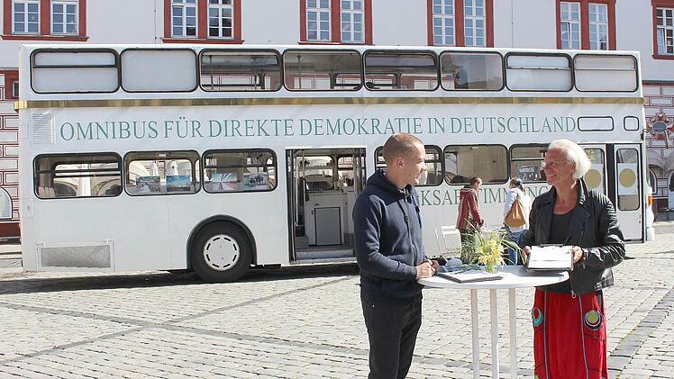 Werner Küppers (rechts) und Christopher Pinnekamp informieren mit zwei weiteren Kollegen über die Initiative, die Volksabstimmungen auch auf Bundesebene einzuführen. Am Freitag, 12. August, steht der Omnibus noch von 9.30 bis 18 Uhr auf dem Coburger Marktplatz. Foto: Ulrike Nauer