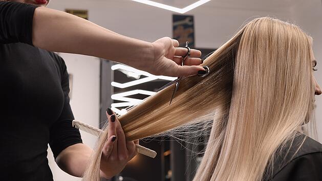 Eine Friseurin schneidet einer Frau in einem Friseursalon die Haare