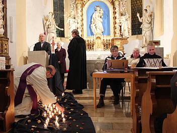 Krankenhausseelsorger Georg Paszek (vorne) setzte die von Pfarrer Fritz Schäfer angezündeten Kerzen auf ein Tuch vor dem Altar. Jedes Licht erinnerte an einen Verstorbenen. Foto: Andreas Dorsch