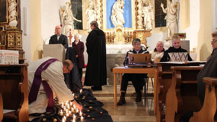 Krankenhausseelsorger Georg Paszek (vorne) setzte die von Pfarrer Fritz Schäfer angezündeten Kerzen auf ein Tuch vor dem Altar. Jedes Licht erinnerte an einen Verstorbenen. Foto: Andreas Dorsch