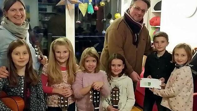Von links Greta, Mathilda, Jule, Lea, Finn und Klara als Vertreter der Gitarrenkinder zusammen mit Ute Fischer-Petersohn bei der Überreichung der Spende an Matthias Simon (Unicef) Foto: red