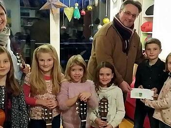 Von links Greta, Mathilda, Jule, Lea, Finn und Klara als Vertreter der Gitarrenkinder zusammen mit Ute Fischer-Petersohn bei der &Uuml;berreichung der Spende an Matthias Simon (Unicef) Foto: red