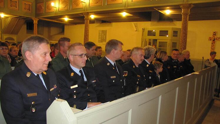 Kreisbrandrat Manfred Lorenz (vorne links) und andere Feuerwehrleute verfolgen andächtig den Jahresgottesdienst der Notfallseelsorge in der Heilig-Kreuz-Kirche. Foto: Martin Koch