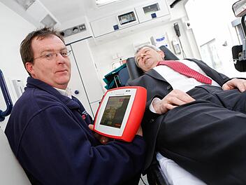 Johannes Arneth, Leiter der BRK-Rettungswache Scheßlitz, demonstriert mit Landrat Johann Kalb als Notfallpatient die Funktionsweise des neuen Tablets, mit dem der Rettungsdienst wichtige Daten schon im Voraus an die Klinik senden kann. Foto: Matthias Hoch