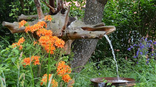 Christine und Norbert Punke (im Bild mit Enkel Oskar) sind in ihrem au&szlig;ergew&ouml;hnlichen Garten &uuml;berall von Kunst umgeben. Der L&auml;rchenwurzelspiralbrunnen ist erst k&uuml;rzlich fertig geworden. Fotos: Dagmar Besand