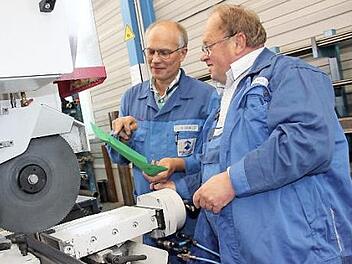 Der Kulmbacher Gerhard Hacker (rechts) ist nach 33 Jahren bei der Maschinenfabrik Fischer in den Ruhestand gegangen. Anhand einer Laufkarte, die Meister Andreas Zeis hält, schneidet er noch einmal ein Rechteckrohr aus Stahl an einer Säge zurecht. Foto: Stephan Stöckel