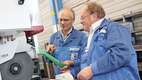 Der Kulmbacher Gerhard Hacker (rechts) ist nach 33 Jahren bei der Maschinenfabrik Fischer in den Ruhestand gegangen. Anhand einer Laufkarte, die Meister Andreas Zeis hält, schneidet er noch einmal ein Rechteckrohr aus Stahl an einer Säge zurecht. Foto: Stephan Stöckel