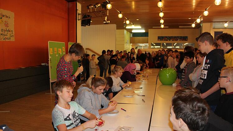 Umweltbewusstsein gehört an der Mittelschule Ebern seit vielen Jahren zu den Bildungszielen. Als Nachfolgerin von Harald Amon, der die Umweltfahne  vor zwölf Jahren erstmals nach Ebern geholt hatte,  moderierte Lehrerin Mareike Fuchs (stehend links) den Schälwettbewerb beim Apfeltag. Mittelschule Ebern/Philipp Arnold