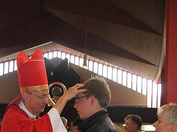 Erzbischof Ludwig Schick zeichnet das Kreuzzeichen auf die Stirn von Firmling André Hauschild . Foto: Sonja Adam