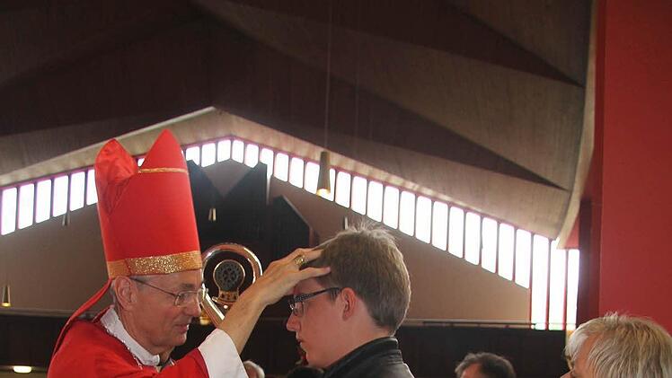 Erzbischof Ludwig Schick zeichnet das Kreuzzeichen auf die Stirn von Firmling André Hauschild . Foto: Sonja Adam