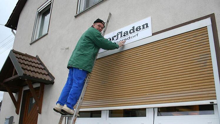 Im Februar 2008 schraubt Roland Schuhmann das Schild am neuen Dorfladen an.