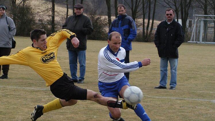 Unser Archivbild vom 8. März 2003 zeigt eine riskante Grätsche von Thulbas Frank Gerlach (links) gegen den Bad Kissinger Spielertrainer Martin Halbig. Klar, dass es in diesem Bezirksliga-Derby ordentlich zur Sache ging. Foto: Hopf