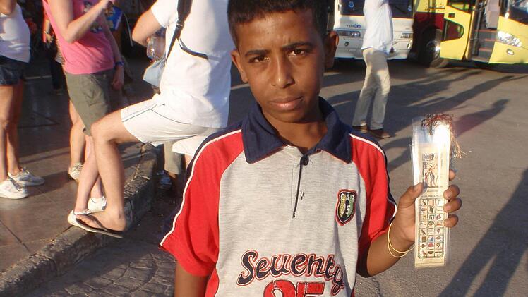 Ein Jungen verkauft an einem Touristenplatz Lesezeichen, anstatt in die Schule zu gehen. Er muss für seine Geschwister mitverdienen.