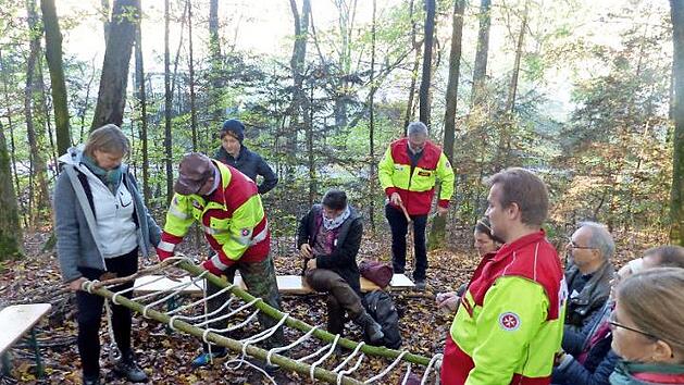 Toni Martin und Florian Eckardt von den Johannitern zeigen den Teilnehmern, wie man mithilfe eines Seils eine Trage bauen kann.  Foto: Johanniter