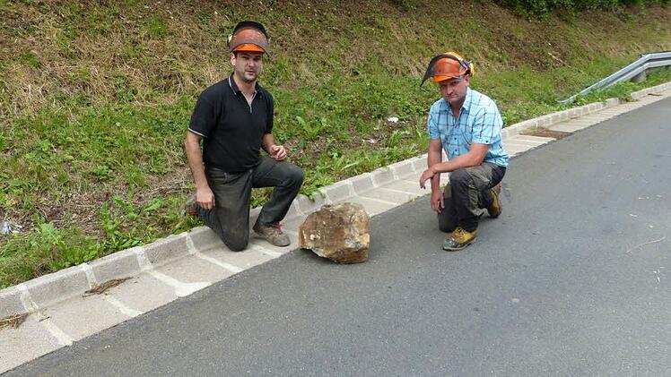 Forstwirtschaftsmeister Michael Milewski (links) und Revierleiter Patrick Lehmann knieen neben dem Stein, der in der Nacht zum auf Donnerstag auf die Kreisstraße gerollt war. Foto: Klaus-Peter Wulf