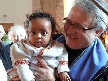 Pfarrer Gerd Kirchner und das jüngste Mitglied der evangelischen Gemeinde: Für das Kind eines Flüchtlingspaares aus Äthiopien hat der Bad Brückenauer Kirchenvorstand die Patenschaft übernommen und will künftig für die kleine Ruth sorgen.Foto: Rolf Pralle