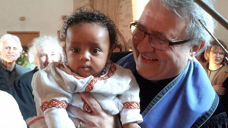 Pfarrer Gerd Kirchner und das jüngste Mitglied der evangelischen Gemeinde: Für das Kind eines Flüchtlingspaares aus Äthiopien hat der Bad Brückenauer Kirchenvorstand die Patenschaft übernommen und will künftig für die kleine Ruth sorgen.Foto: Rolf Pralle