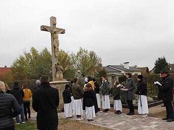 Pfarrer Matthias Steffel weiht das renovierte Sandsteinkreuz am Friedhof in Willersdorf. Es wurde im Rahmen der Neugestaltung saniert. Foto: Mathias Erlwein