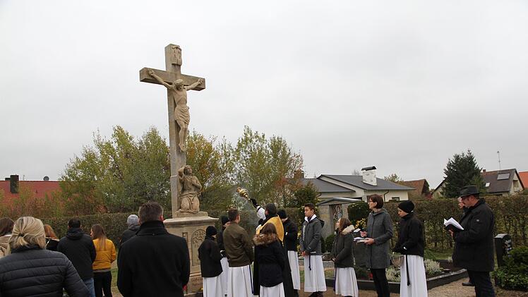 Pfarrer Matthias Steffel weiht das renovierte Sandsteinkreuz am Friedhof in Willersdorf. Es wurde im Rahmen der Neugestaltung saniert. Foto: Mathias Erlwein