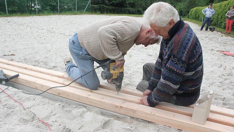 Gerhard (links) und Georg Grebner befestigen die Kanthölzer rund um die Beachvolleyballfelder.  Foto: Friedwald Schedel