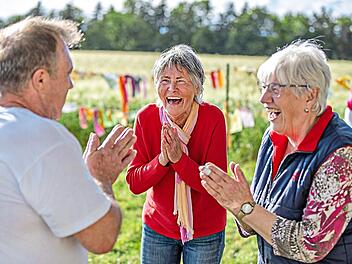 Renate F&ouml;rster steht zwischen den Teilnehmern und lacht herzlich. Ihr angeleitetes Lachen steckt viele in der Gruppe an. Ren&eacute; Ruprecht