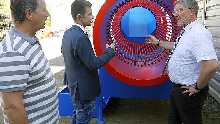 Ein bisschen auffallen darf schon sein: Die kräftigen Farben gehören bei der Brennholz-Reinigungstrommel dazu, erklären Norbert Dressel und Dominic Dressel Landrat Michael Busch bei der Führung durch das Außengelände des Metallbauspezialisten. Foto: Berthold Köhler