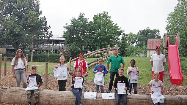 DLRG-Bufdi Sophia Fischer, Marliese B&auml;r (DLRG-Kreisverband Kronach), Stephan Preisz (AOK-Direktion Coburg) und Richard B&auml;r (DLRG-Kreisverband Kronach) (hinten von links) freuen sich gemeinsam mit einigen "Sicheren Schwimmern" der Lucas-Cranach-Schule &uuml;ber die erneut sehr erfolgreiche Aktion.  Foto: hs