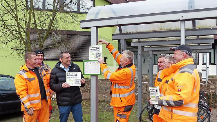Nicht nur an Bushaltestellen wie hier, sondern auch an Straßenlaternen werden Röttenbacher Bauhofmitarbeiter die Schilder anbringen, damit Bürger Schäden schnell per Handy melden können. Bürgermeister Ludwig Wahl (Dritter von links) freut sich, diesen Service anbieten zu können.  Foto: Pauline Lindner