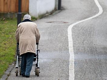Eine &auml;ltere Frau geht mit einem Rollator einen Weg entlang. Foto: Armin Weigel/dpa