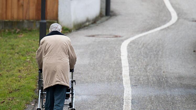 Eine &auml;ltere Frau geht mit einem Rollator einen Weg entlang. Foto: Armin Weigel/dpa