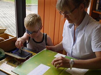 Hannes Lösch darf Marita Römer beim Abstempeln der Bücher helfen (linkes Bild). Sigrid Lösch (r.) berät Ursula Oesterer bei der Buchauswahl.   Fotos: Pauline Lindner