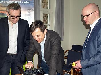 Bürgermeister Jens Korn (Mitte) versuchte sich unter Anleitung des Thüga-Geschäftsführers Peter Horn (links) in der Handhabung eines Spleißgerätes, das Glasfasern verbinden kann.  Foto: Susanne Deuerling