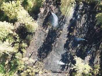 Die Luftaufnahme zeigt die Feuerwehren im Einsatz bei der Brandbekämpfung in dem Waldstück zwischen Eyrichshof und Fischbach. Das Bild wurde von Stefan Funck mit Hilfe einer Drohne des Bayerischen Roten Kreuzes aufgenommen.